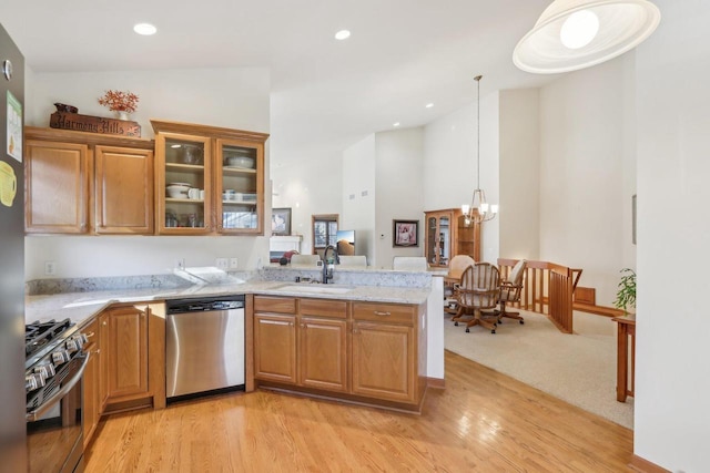 kitchen with appliances with stainless steel finishes, decorative light fixtures, sink, a notable chandelier, and light hardwood / wood-style flooring