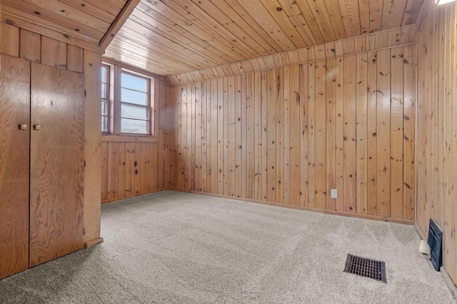 empty room featuring carpet floors, wood ceiling, and wooden walls