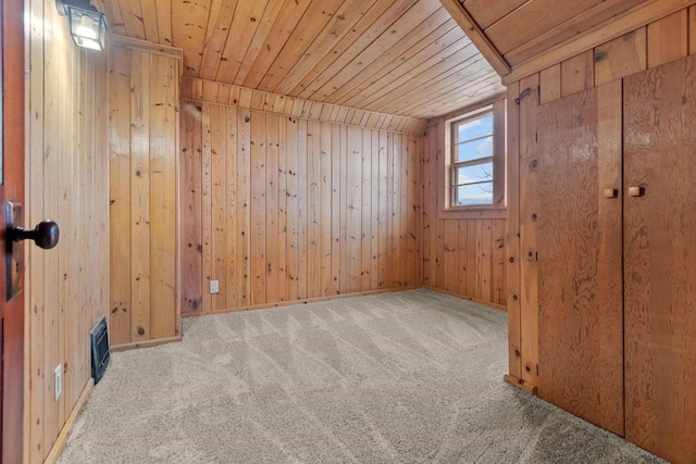 carpeted empty room with wooden ceiling, lofted ceiling, and wood walls