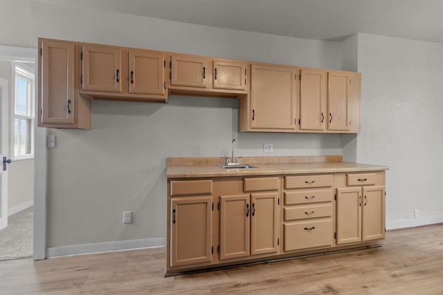 kitchen with light brown cabinetry, sink, and light hardwood / wood-style flooring