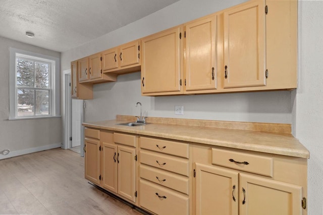 kitchen with light brown cabinetry, sink, and a textured ceiling