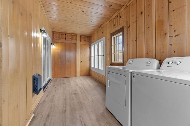 laundry area with light hardwood / wood-style floors, washer and clothes dryer, wood ceiling, and wooden walls