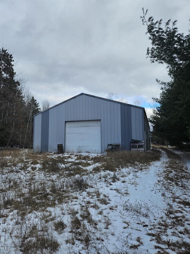 snow covered structure featuring a garage