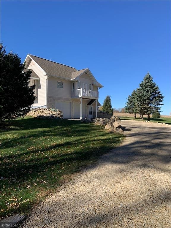 view of property exterior featuring a lawn, a balcony, and a garage