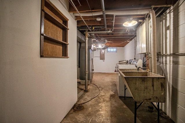 basement with heating unit, washer and clothes dryer, sink, and electric panel