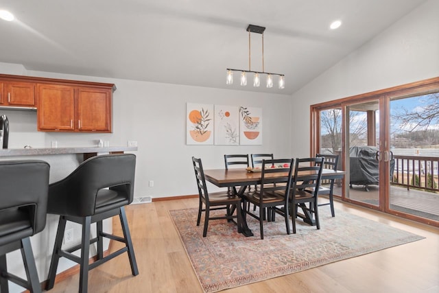 dining room with lofted ceiling and light wood-type flooring