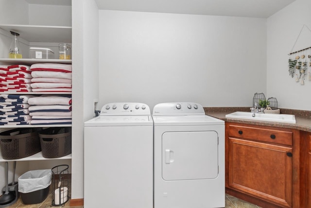 clothes washing area featuring light tile patterned floors, sink, washing machine and clothes dryer, and cabinets