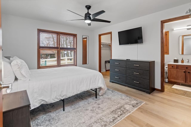 bedroom featuring ceiling fan, ensuite bathroom, light hardwood / wood-style floors, a spacious closet, and a closet