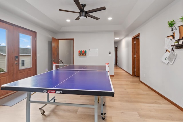 game room featuring ceiling fan, light hardwood / wood-style flooring, and a raised ceiling