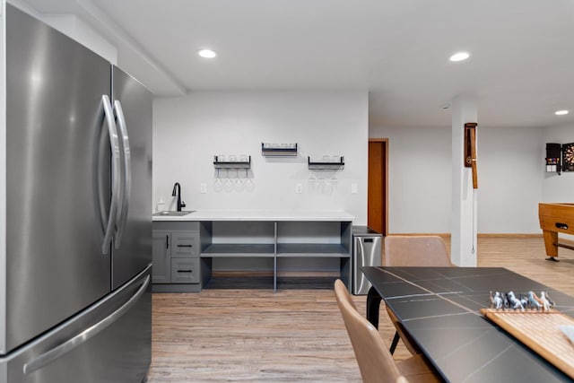 kitchen with tile countertops, sink, stainless steel refrigerator, light wood-type flooring, and gray cabinetry