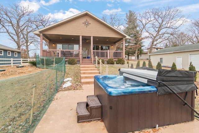 rear view of property with a porch and a hot tub