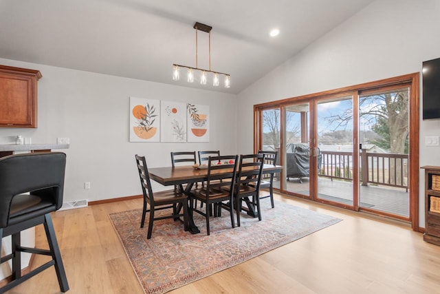 dining room with light hardwood / wood-style floors, a notable chandelier, and vaulted ceiling