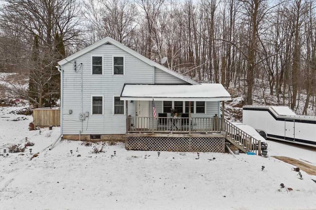 snow covered back of property with covered porch