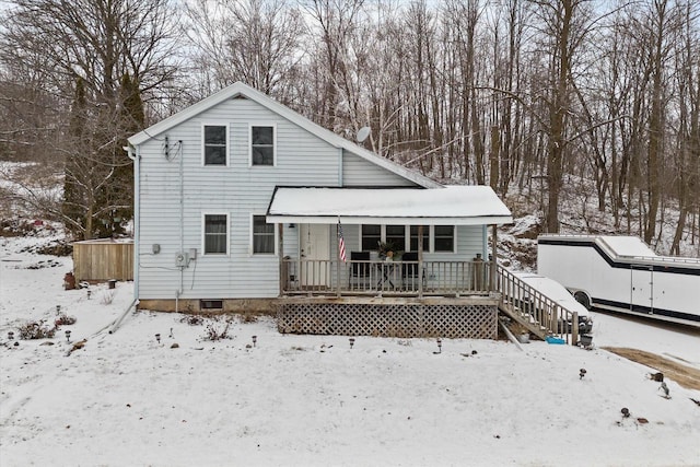 snow covered back of property with covered porch