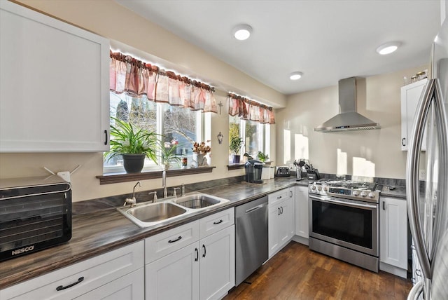 kitchen featuring white cabinetry, stainless steel appliances, dark wood-type flooring, wall chimney range hood, and sink