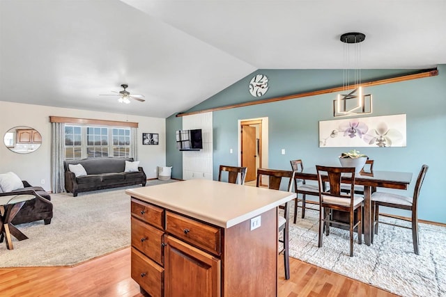 kitchen with a kitchen bar, ceiling fan, vaulted ceiling, a kitchen island, and pendant lighting