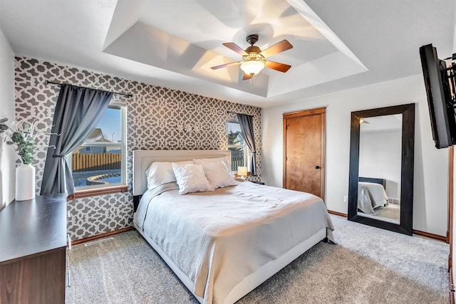 bedroom featuring ceiling fan, light colored carpet, and a raised ceiling