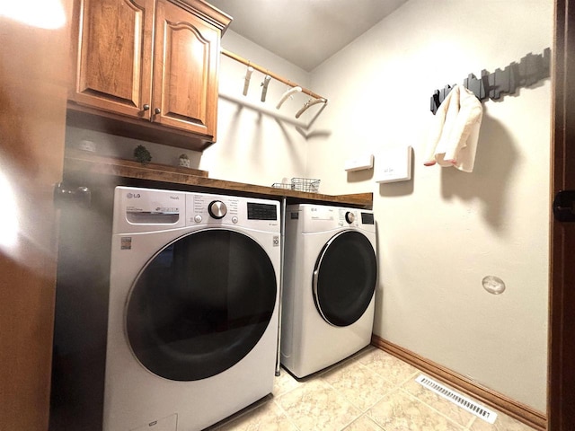 clothes washing area with cabinets, independent washer and dryer, and light tile patterned flooring