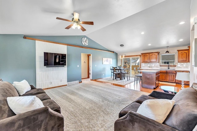 living room featuring ceiling fan, sink, light wood-type flooring, and vaulted ceiling