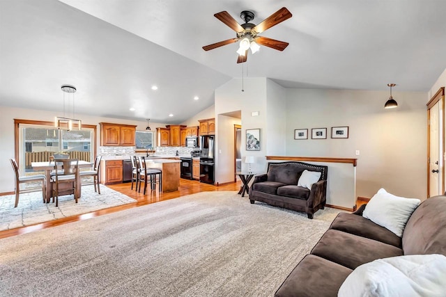 living room featuring ceiling fan, vaulted ceiling, sink, and light hardwood / wood-style flooring