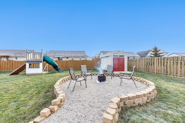 view of yard featuring a playground, a fire pit, and a storage unit