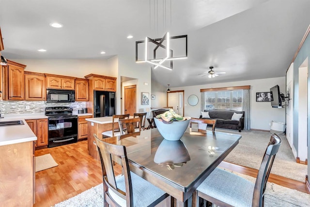 dining space with ceiling fan, sink, light hardwood / wood-style flooring, and lofted ceiling