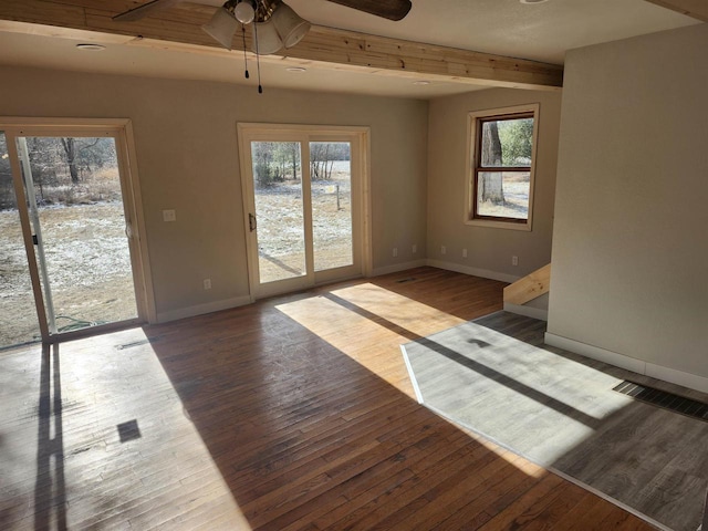 empty room featuring ceiling fan, wood-type flooring, and beamed ceiling