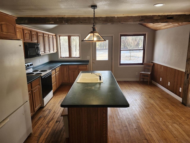 kitchen featuring wood walls, white appliances, beam ceiling, and a kitchen island