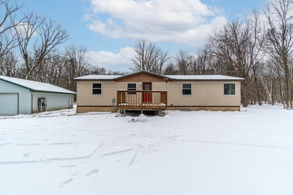 view of front of home with a garage, a wooden deck, and an outbuilding