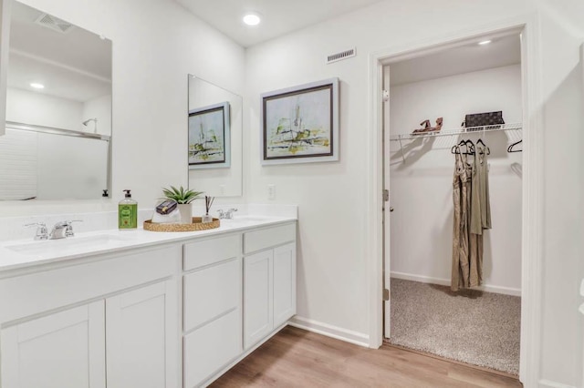 bathroom with a shower with shower door, vanity, and wood-type flooring