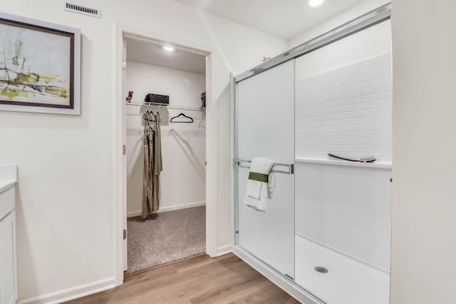 bathroom featuring walk in shower, vanity, and hardwood / wood-style floors