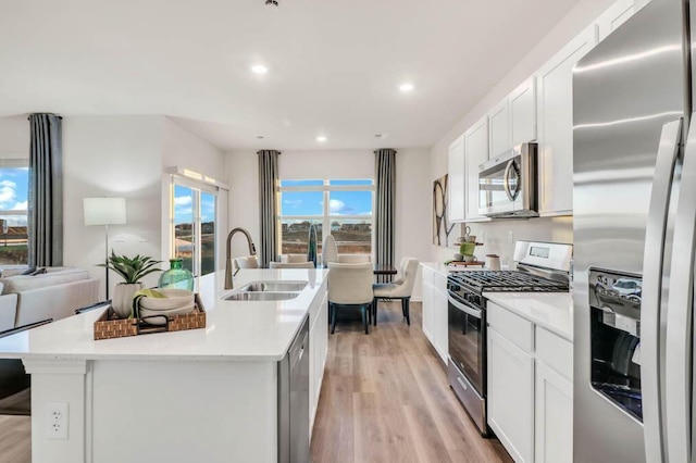 kitchen with sink, white cabinets, stainless steel appliances, and an island with sink