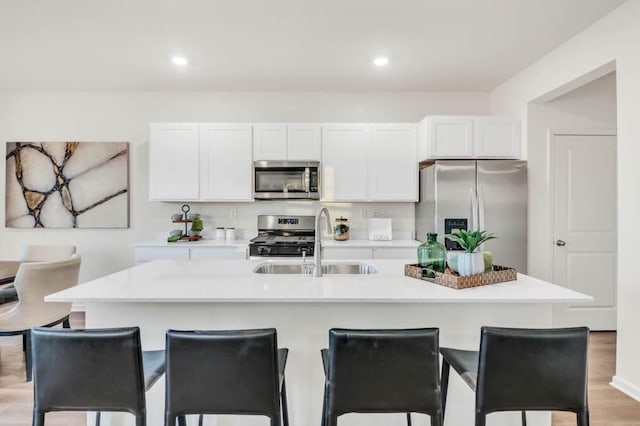 kitchen with sink, white cabinetry, appliances with stainless steel finishes, and a center island with sink