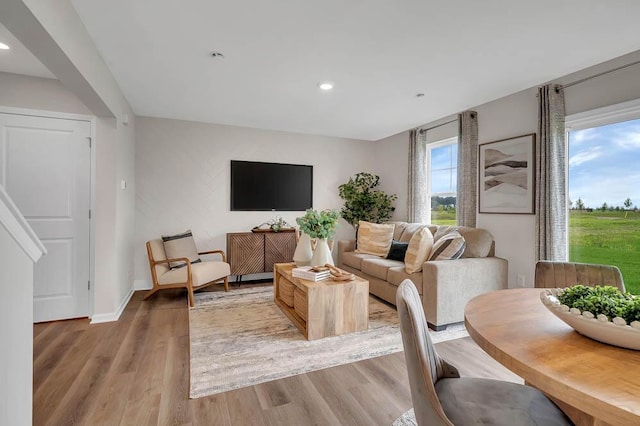 living room featuring recessed lighting, baseboards, and light wood finished floors