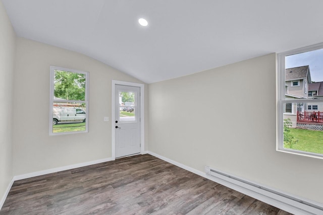 spare room with lofted ceiling, baseboard heating, and dark wood-type flooring