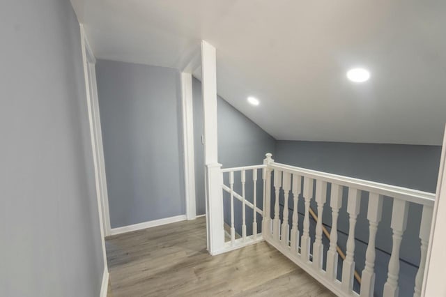 hallway with vaulted ceiling and light hardwood / wood-style floors