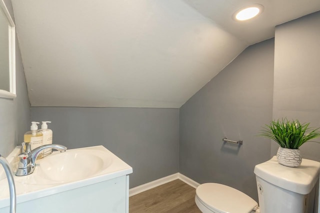 bathroom featuring vaulted ceiling, toilet, hardwood / wood-style flooring, and vanity