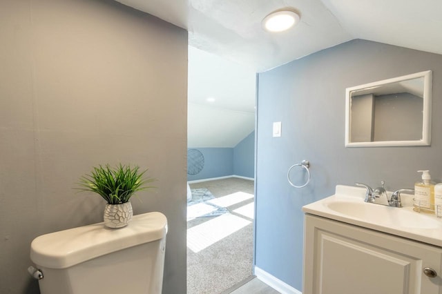 bathroom with toilet, vanity, and vaulted ceiling