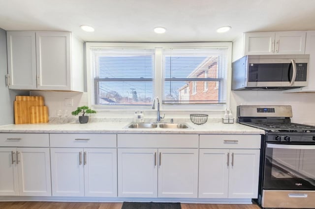 kitchen with stainless steel appliances, light hardwood / wood-style flooring, white cabinets, and sink