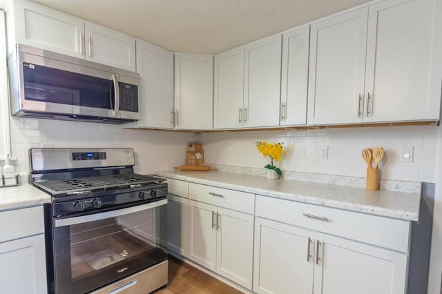 kitchen with decorative backsplash, appliances with stainless steel finishes, and white cabinetry