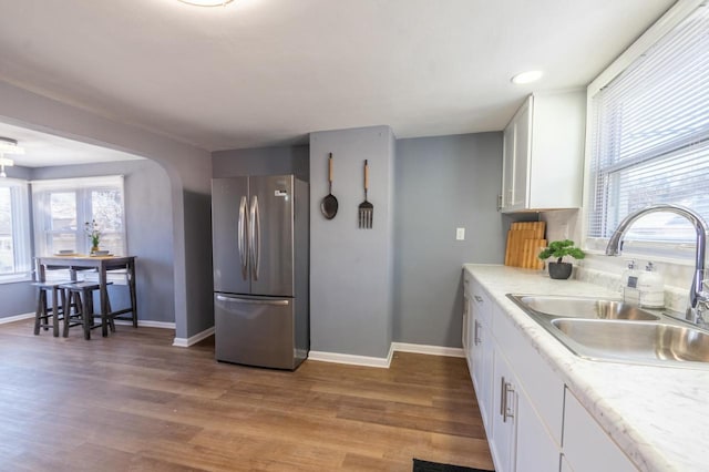 kitchen featuring hardwood / wood-style floors, sink, white cabinets, and stainless steel refrigerator