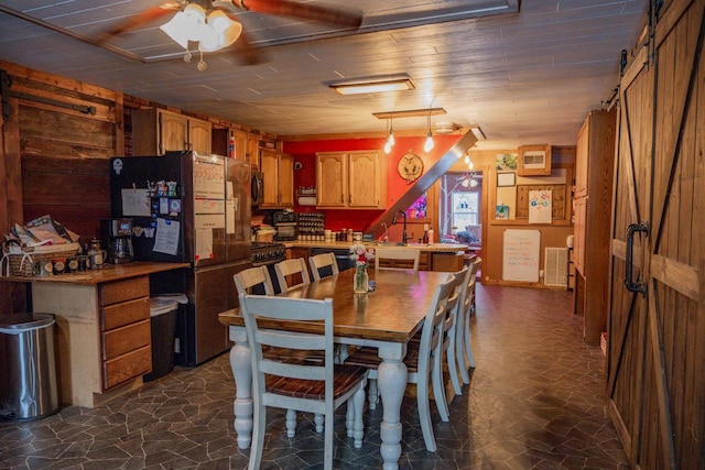 dining area with ceiling fan, wood ceiling, a barn door, and wooden walls