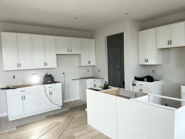 kitchen with white cabinets, a center island, and light hardwood / wood-style flooring