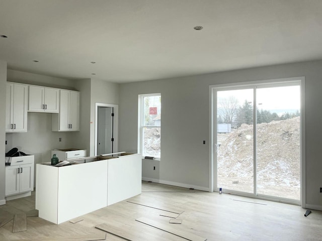 kitchen featuring white cabinets, light hardwood / wood-style flooring, and a healthy amount of sunlight