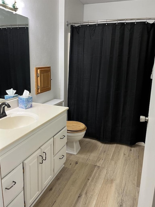 bathroom with wood-type flooring, toilet, and vanity