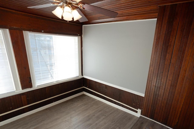 unfurnished room featuring hardwood / wood-style floors, wooden walls, wooden ceiling, ceiling fan, and crown molding