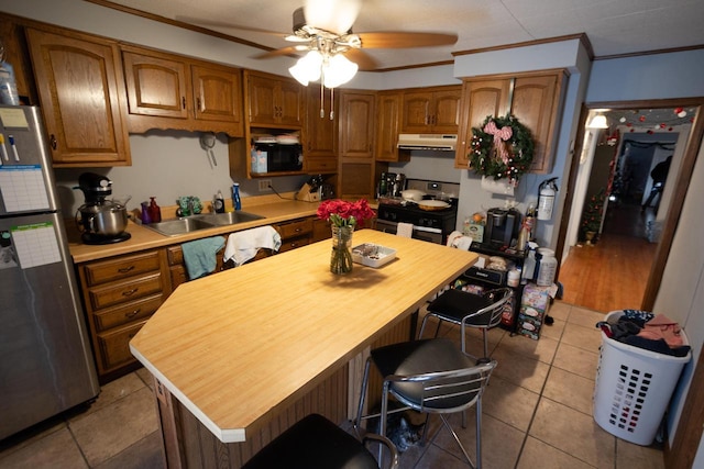 kitchen with stainless steel appliances, sink, ceiling fan, a breakfast bar, and crown molding