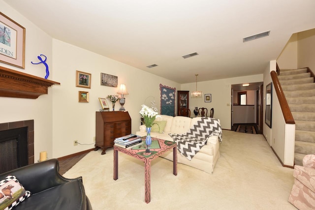 carpeted living room with a tiled fireplace and a notable chandelier