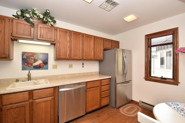 kitchen with a baseboard heating unit, sink, stainless steel appliances, and light hardwood / wood-style flooring