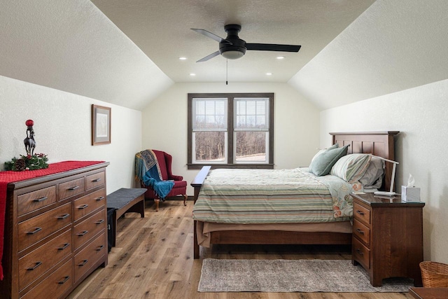 bedroom with ceiling fan, vaulted ceiling, a textured ceiling, and light hardwood / wood-style floors